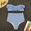 Blue and white striped bikini set on a textured surface with a straw hat and pineapple decorations.
