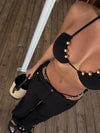 Person wearing a black outfit with gold embellishments on a wooden floor.