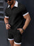 Man wearing a black outfit with white accents against a dark background