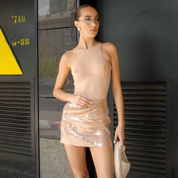 Woman wearing a sheer top and sequin skirt on a white background