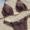 Brown bikini set with matching face mask on a woven surface