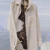 Beige trench coat with leopard print lining on a blurred sky background