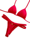Red bikini set on a decorative wooden surface with a visible brand tag.