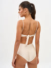 Woman wearing a beige swimsuit with thin straps on a white background