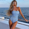 Woman in a blue swimsuit holding a glass of wine on a boat with ocean view
