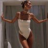 Woman wearing a white swimsuit with floral details against a neutral background