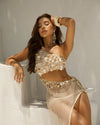 Woman wearing a decorative top and skirt against a neutral background