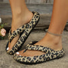 Leopard print flip-flops worn by a person on a stone surface with flowers in the background.