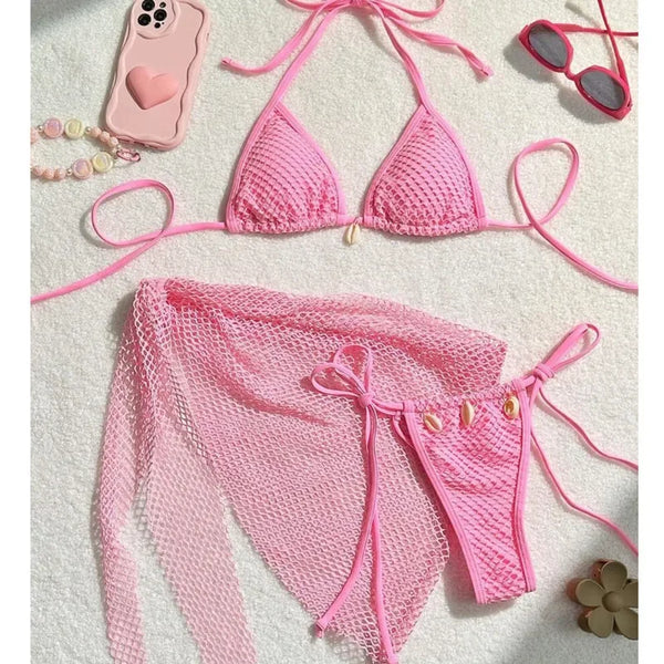 Pink crochet bikini set on a white surface with accessories.