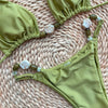 Green bikini set with beaded straps on a woven surface