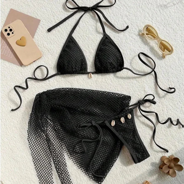 Black bikini set with matching cover-up on a light surface with accessories.