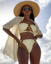 Woman in a yellow bikini and straw hat against a cloudy sky