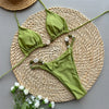 Green bikini set on a woven mat with flowers on a gray background
