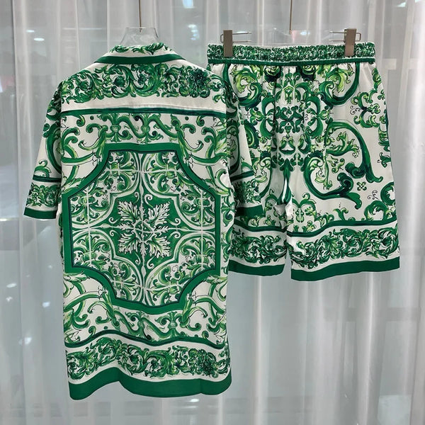 Green and white patterned shirt and shorts set on a hanger against a light curtain background.
