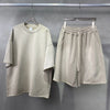 Beige t-shirt and shorts set hanging on a gray background