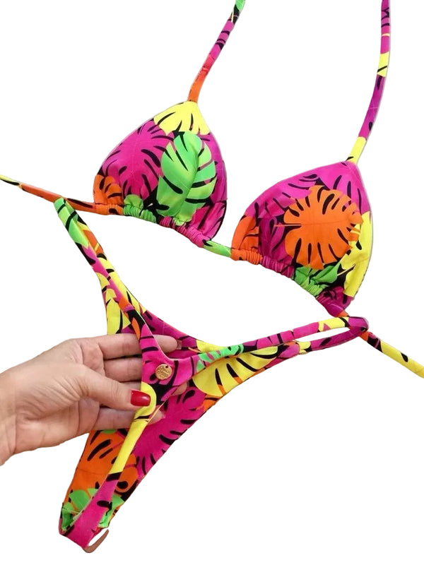 Colorful bikini set with leaf patterns held by a hand against a light background