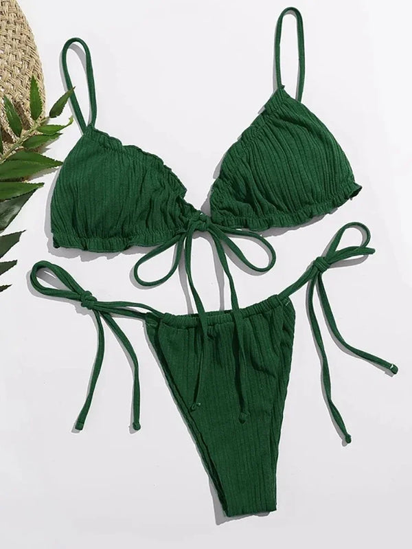 Green bikini set on a white background with a straw hat and leaves.