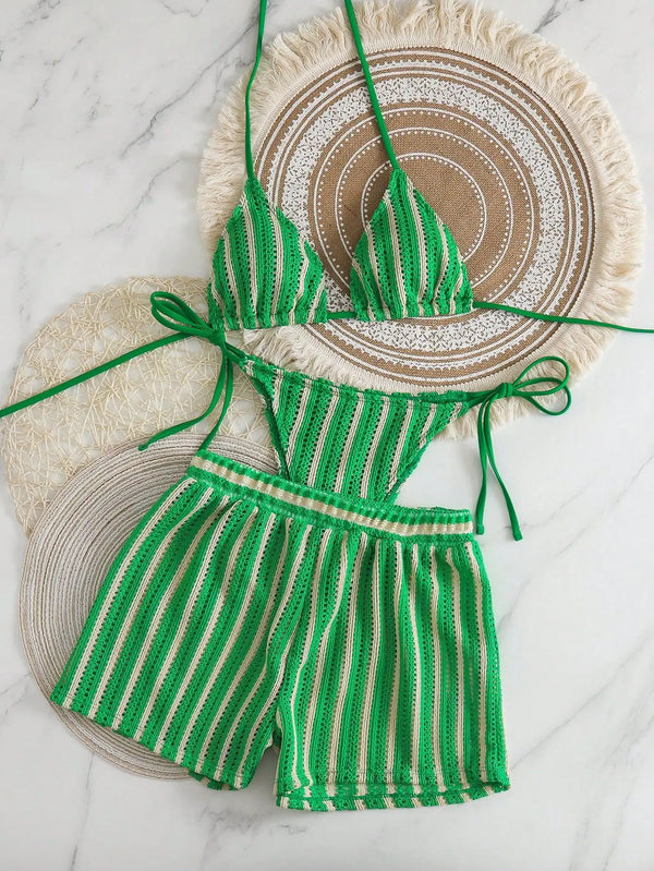 Green and white striped bikini set on a marble surface with decorative plates.