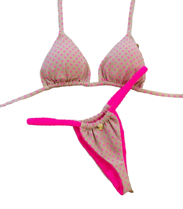 Pink polka dot bikini set with matching pink straps on a decorative wooden stand.