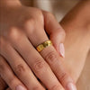 Close-up of a hand wearing a gold ring with a blurred background
