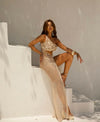 Woman in a gold dress posing against a white wall
